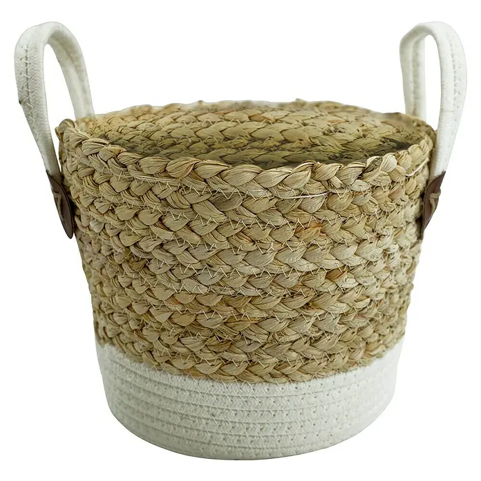Korb Grasgeflecht - Natur/Weiß, Ø x H: 21 x 15,5 cm - Nahaufnahme eines dekorativen Korbs aus Naturmaterialien mit weißen Griffen und einem weißen Sockel.