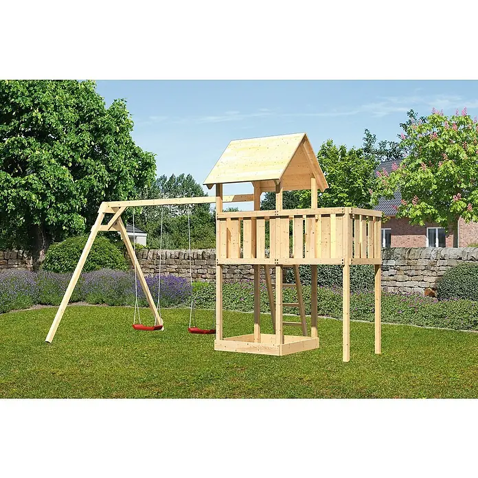 Karibu Kinderspielturm Lotti Set 19 - L x B x H: 264 x 454 x 291 cm, Natur - Ein hölzernes Spielhaus mit Schaukel auf einem grünen Rasen vor einer Steinmauer. Perfekt für stundenlangen Spaß im Freien.