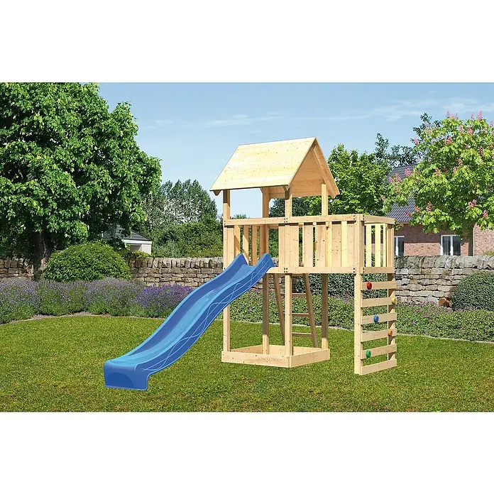 Karibu Kinderspielturm Lotti Set 41 - L x B x H: 107 x 214 x 291 cm, Natur/Blau - Ein hölzerner Spielturm mit blauer Rutsche und Kletterwand steht in einem Garten mit Bäumen und Blumen.