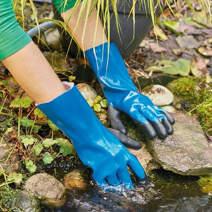 Gardol Gartenhandschuhe - Handschuhgröße: 9, Blau - Nahaufnahme einer Person, die blaue Gartenhandschuhe mit schwarzen Fingerspitzen trägt, während sie in einem Gartenteich arbeitet.