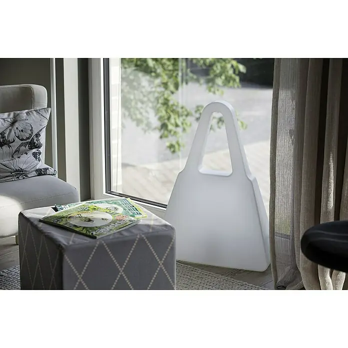8 Seasons Design Shining LED-Solar-Dekoleuchte Bag - Weiß, L x B x H: 19 x 55 x 75 cm - Eine moderne, weiße Handtaschen-Bodenleuchte steht neben einem Fenster und verleiht dem Raum eine stilvolle Note.