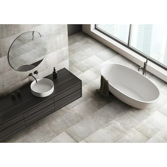 Feinsteinzeugfliese Urban Beton - 30 x 60,4 cm, Grau, Matt - Elegantes Badezimmer mit ovaler Badewanne, Waschtisch mit Aufsatzwaschbecken und großformatigen Fliesen in Grau.
