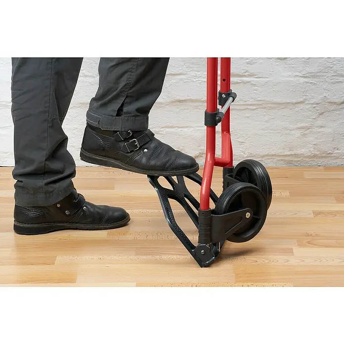 Carretilla de transporte plegable - Capacidad de carga: 60 kg, Aluminio - Una persona acciona con el pie un carro de mano plegable rojo. Ideal para transportar objetos pesados fácilmente.