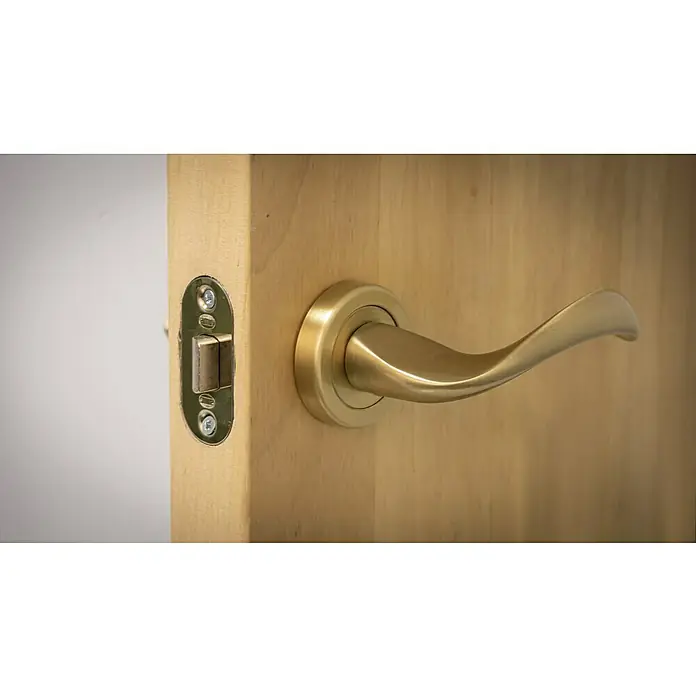 Resbalón 8-45 redondo latón - Apto para: Puertas de madera, Sin cerradura - Primer plano de un tirador de puerta dorado en una puerta de madera. El tirador tiene un diseño moderno y elegante y es de metal.