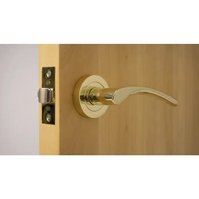 Resbalón 8-45 cuadrado latón - Apto para: Puertas de madera, Sin cerradura - Primer plano de una manija de puerta dorada con cerradura en una puerta de madera. La manija está curvada y pulida.
