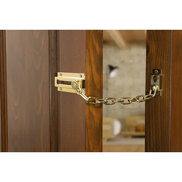 Cadena de puerta - Longitud de cadena: 20 cm, Latón, Pulido - Primer plano de una cadena de seguridad dorada para puerta sujeta a una puerta de madera, que brinda seguridad y protección.