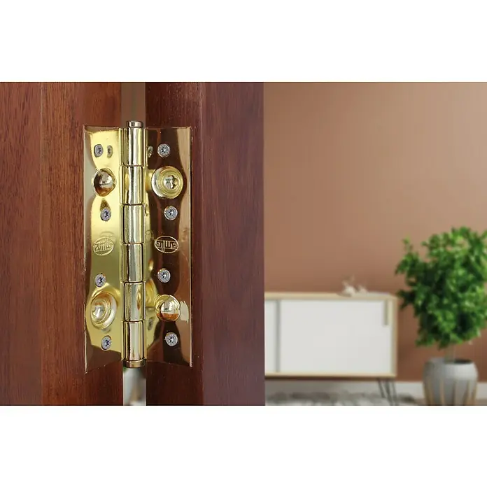 Bisagra mod. 565 - 150 x 80 x 3 mm, Oro, 1 ud. - Primer plano de una bisagra de puerta dorada y brillante fijada a una puerta de madera oscura. Vista detallada con tornillos y el logo del fabricante.