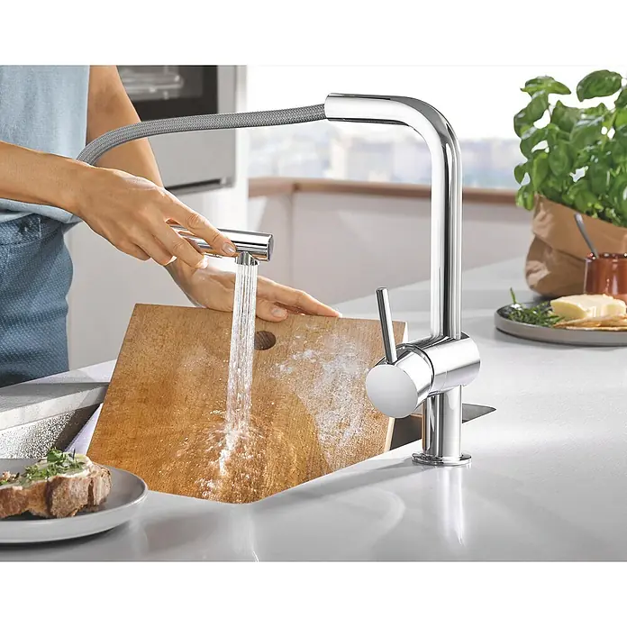 Grohe Spültischarmatur Minta - L-Auslauf, Chrom, Glänzend, Anzahl Strahlarten: 2 Stk. - Eine moderne Küchenarmatur aus Chrom wird verwendet, um ein Schneidebrett unter fließendem Wasser zu reinigen. Elegantes Design für jede Küche.