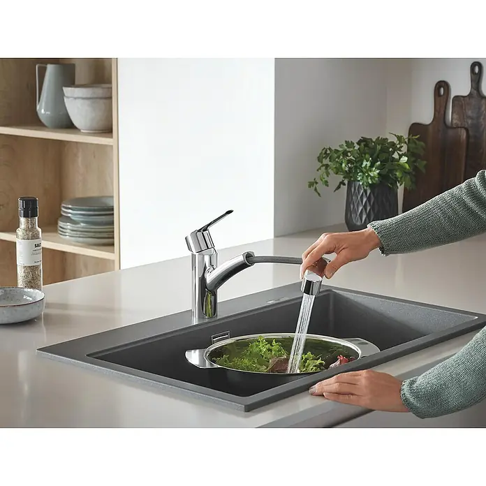 Grohe QuickFix Spültischarmatur Start - Chrom, Ausziehbar, Glänzend - Küchenszene mit einer Person, die Salat in einem Spülbecken mit einer BLANCO Küchenarmatur wäscht, die Wasser ausgibt.