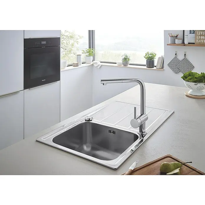 Grohe Spültischarmatur Minta - L-Auslauf, Chrom, Glänzend, Ausziehbar - Einbauküche mit Spüle aus Edelstahl und moderner Armatur unter einem Fenster mit natürlichem Licht.
