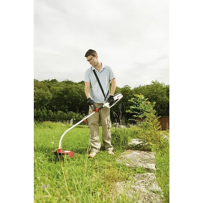AL-KO Elektro-Rasentrimmer BC 1000 E - 1.000 W, Schnittbreite Faden: 35 cm - Ein Mann benutzt einen AL-KO Rasentrimmer mit Akku und Tragegurt, um Gras zu schneiden, wobei der Fokus auf dem Rasentrimmer liegt.