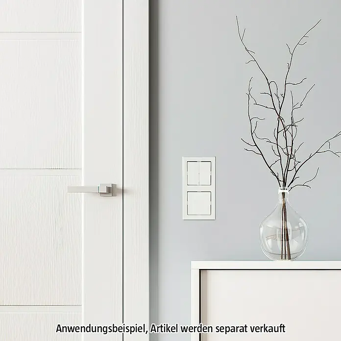 Merten 1-M Serienschalterwippe 432519 - Polarweiß, Hochglänzend, Kunststoff, Unterputzmontage - Ein doppelter Lichtschalter in Weiß ist an einer grauen Wand neben einer weißen Tür montiert. Dekorative Zweige stehen in einer Glasvase.