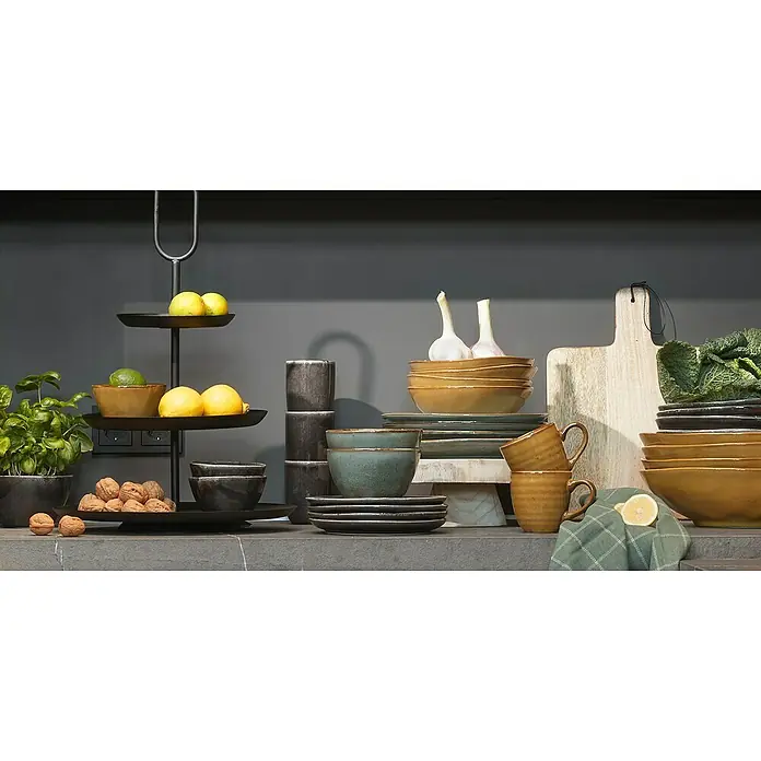 Trinkbecher Tabo - Ø x H: 7,5 x 10 cm, Schwarz, Keramik - Ein Arrangement aus Schüsseln, Tellern und Tassen in verschiedenen Farben auf einer Küchenarbeitsplatte mit Obst und Gemüse.