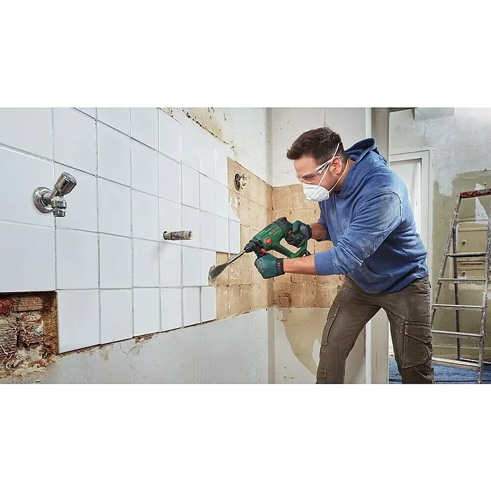 Bosch Professional AMPShare 18V Akku-Kombihammer UniversalHammer 18V - 18 V, 1 Akku, 4 Ah, 2 J - Ein Mann, der eine Bosch-Bohrmaschine benutzt, um Fliesen von einer Wand zu entfernen. Er trägt Schutzkleidung für seine Sicherheit.