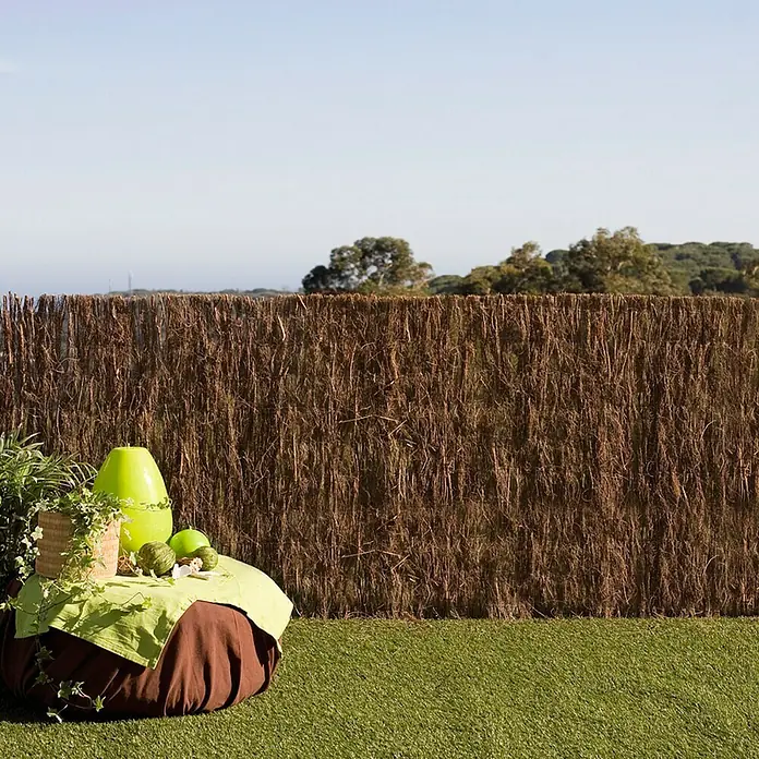 Brezo Bruc Plus 2 - 5 x 1,5 m, Marrón - Escena de jardín decorativa con una robusta valla de privacidad, creando un ambiente exterior natural y tranquilo.