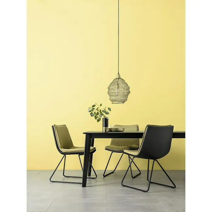 SCHÖNER WOHNEN-Farbe Wandfarbe Designfarbe - Freundliches Goldgelb, Matt, 2,5 l, Konservierungsmittelfrei - Esszimmer mit schwarzem Esstisch, drei Stühlen und einer dekorativen Lampe, die von der Decke hängt.