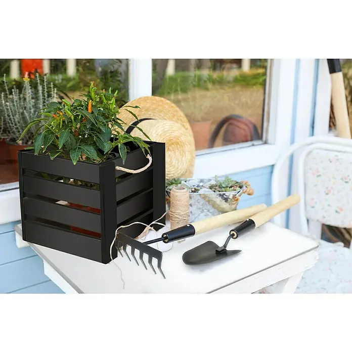 Kompaktplatte nach MaßAnthrazit, Max. Zuschnittsmaß: 2.800 x 1.300 mm, Stärke: 6 mm - Gartenszene mit schwarzem Pflanzkasten, Werkzeugen und Strohhut auf einem weißen Tisch. Dekorative und funktionale Gartenausstattung.