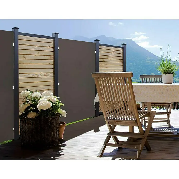 Kompaktplatte nach Maß - Braun, Stärke: 6 mm - Außenaufnahme einer Sichtschutzwand aus Holz und Metall auf einer Terrasse, mit Gartenmöbeln und Bergpanorama im Hintergrund.