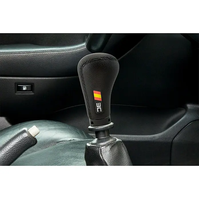 Funda para palanca de cambios Cobra - Apto para: Coches - Primer plano de un pomo de cambio JE negro con una bandera alemana dentro de un coche.