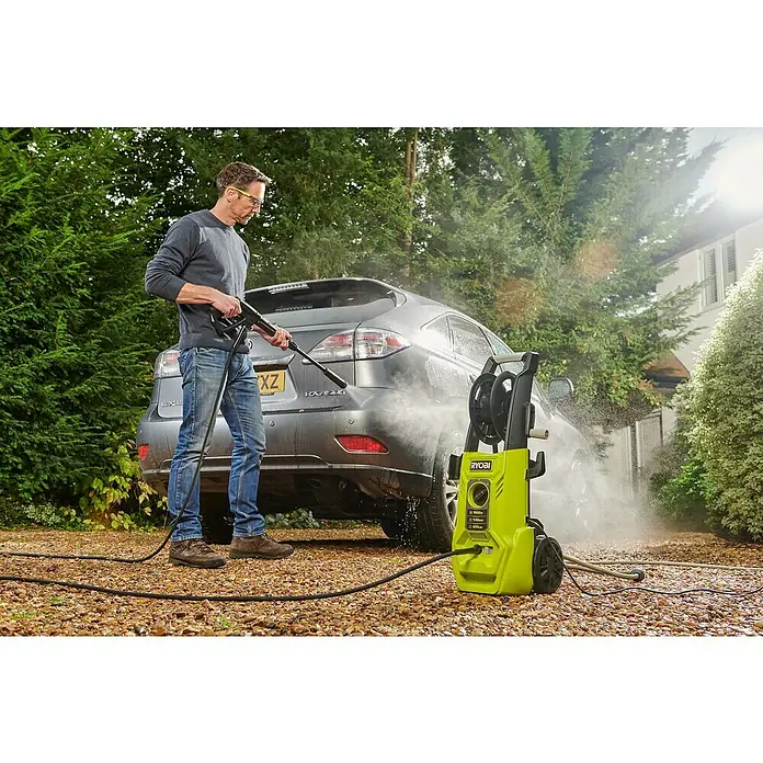 Ryobi Hochdruckreiniger RY140PWA - 1.800 W - Ein Mann benutzt einen Ryobi Hochdruckreiniger, um ein graues Auto im Freien zu waschen. Der Hochdruckreiniger ist gelb und schwarz.