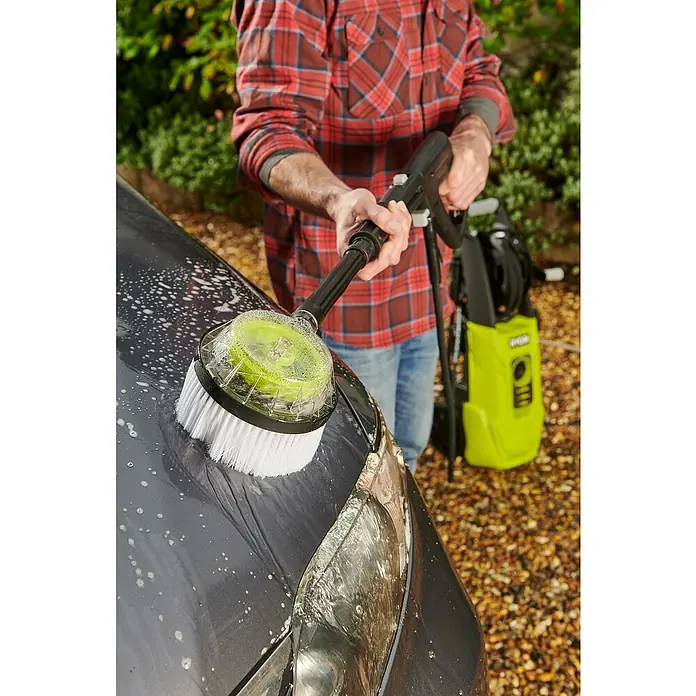 Ryobi Hochdruckreiniger RY150PWA - 2.000 W - Ein Mann wäscht mit einer rotierenden Bürste und einem Hochdruckreiniger ein Auto. Der Hochdruckreiniger ist gelb und steht im Hintergrund.