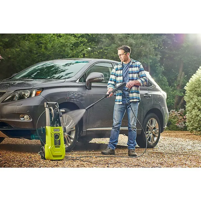 Ryobi Hochdruckreiniger RY150PWA - 2.000 W - Ein Mann benutzt einen Ryobi-Hochdruckreiniger, um ein graues Auto zu waschen. Das Gerät steht neben dem Auto und sprüht Wasser auf den Reifen.
