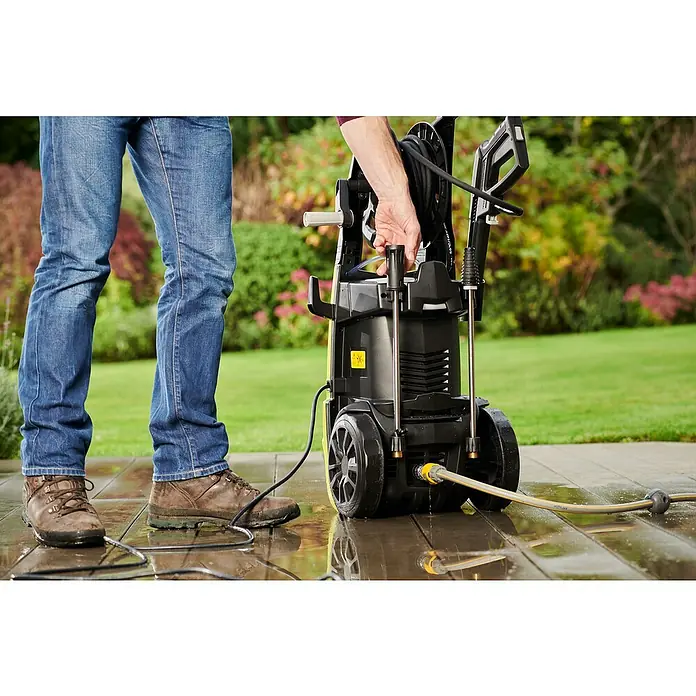 Ryobi Hochdruckreiniger RY170PWA - 2.500 W - Ein Mann bedient einen Kärcher Hochdruckreiniger im Garten. Der Hochdruckreiniger steht auf einer Holzterrasse.