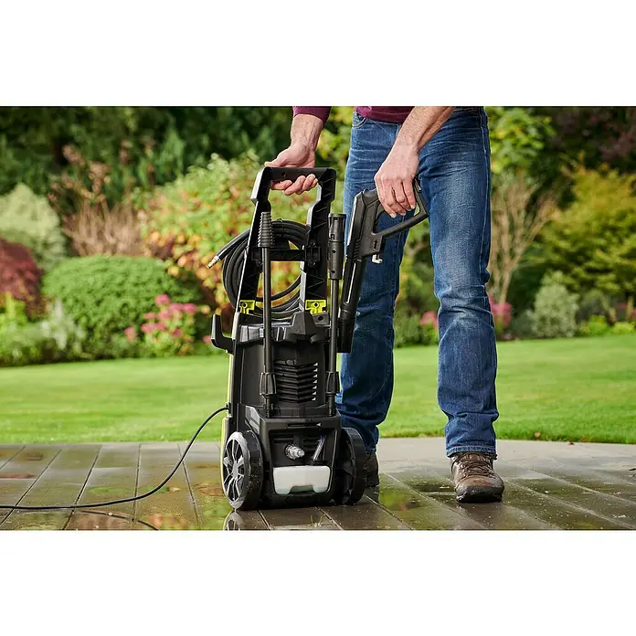 Ryobi Hochdruckreiniger RY130PWA - 1.600 W - Eine Nahaufnahme eines Mannes, der einen schwarzen Hochdruckreiniger mit gelben Akzenten auf einer Terrasse hält.
