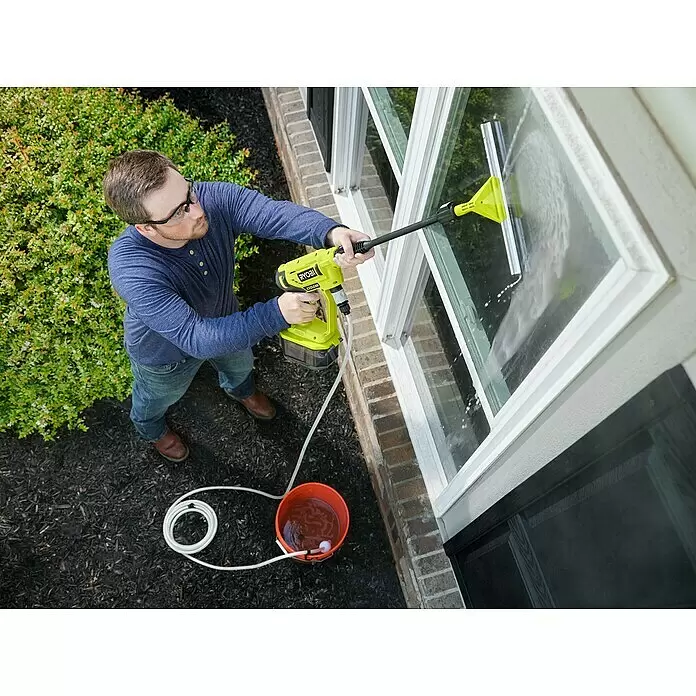 Ryobi Fensterwascher RAC 763 - Einsatzbereich: Haushalt, Ausstattung: Integrierte Spüldüse - Mann reinigt ein Fenster mit einem gelben Ryobi EZClean Hochdruckreiniger und Abzieher, der an einen Wassereimer angeschlossen ist.