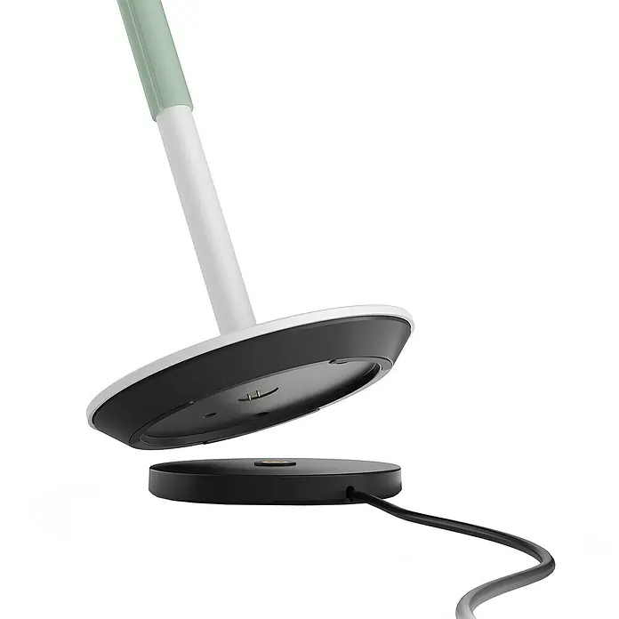 Philips Hue Akku-Tischleuchte Go Portable6,2 W, L x B x H: 21,9 x 20,9 x 38,8 cm, Weiß, Mehrfarbig - Draufsicht auf die Ladestation einer Lampe mit weißem und grünem Stiel, die zum Aufladen bereit ist, mit Blick auf das Kabel.