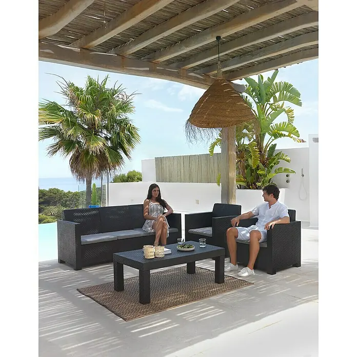 Shaf Conjunto de muebles Belice - 4 pzs., Polipropileno, Grafito - Sofá de exterior elegante con mesa de centro y sillón de ratán en una terraza soleada con dosel.