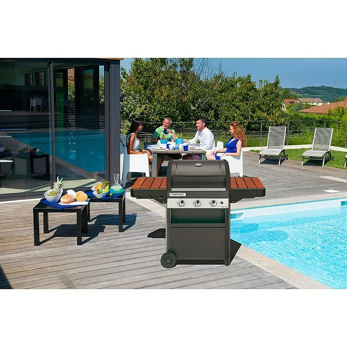 Campingaz Barbacoa de gas Classic WLD - Superficie de la parrilla (An x Pr): 61 x 46 cm, Número de quemadores: 3 - La elegante parrilla de gas CAMPINGAZ se encuentra en una terraza de madera cerca de la piscina, ideal para una barbacoa al aire libre con amigos.