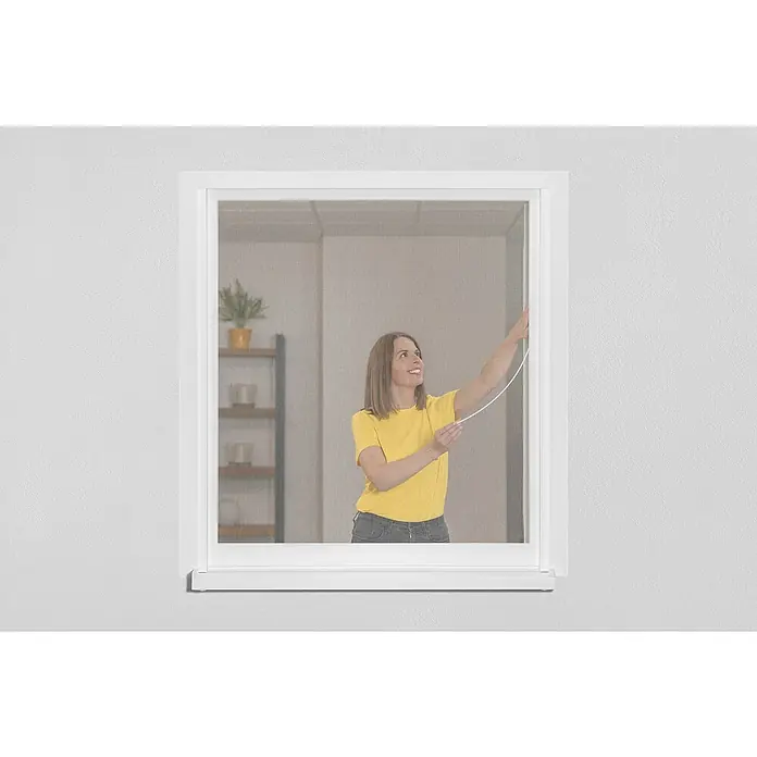 Schellenberg Mosquitera EasyClick - An x Al: 130 x 150 cm, Montaje de la mosquitera: Pegado, Color bastidor: Blanco - Mujer opera un mosquitero enrollable en una ventana, proporcionando una vista clara mientras mantiene a los insectos molestos fuera.