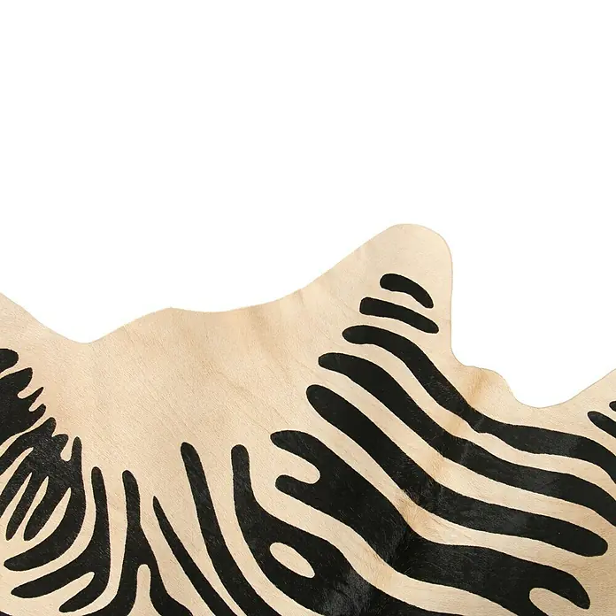 Esbeco Kuhfell - 100 % Echtfell, Zebra - Nahaufnahme eines Zebra-Kuhfellteppichs mit beigen und schwarzen Streifen, der ein stilvolles und exotisches Ambiente vermittelt.