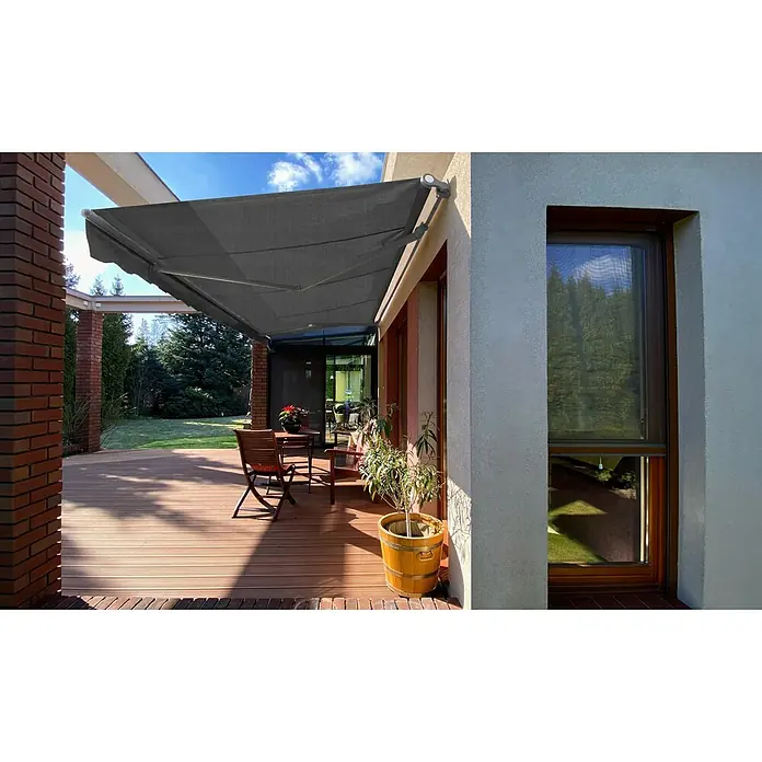SM Gelenkarmmarkise T-5406/107 - Grau, Farbe Gestell: Weißaluminium, Breite: 3,6 m, Ausfall: 2,5 m - Eine graue Markise schützt eine Holzterrasse mit Tisch und Stühlen vor der Sonne und bietet einen angenehmen Schattenbereich.