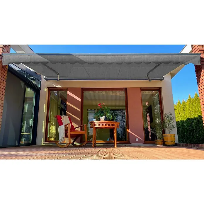 SM Gelenkarmmarkise REC-196Hellgrau, Farbe Gestell: Weißaluminium, Breite: 3,6 m, Ausfall: 2,5 m - Graue Terrassenmarkise über einer Terrasse mit Holzdeck, Stuhl und Tisch, die Schatten spendet und eine gemütliche Atmosphäre schafft.
