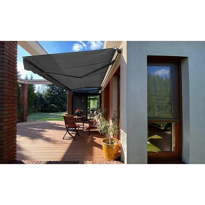 SM Gelenkarmmarkise T-5406/107Grau, Farbe Gestell: Anthrazitgrau, Breite: 5 m, Ausfall: 3 m - Eine graue Terrassenmarkise spendet Schatten auf einer Holzterrasse mit Tisch und Stühlen, die an ein modernes Haus angrenzt.