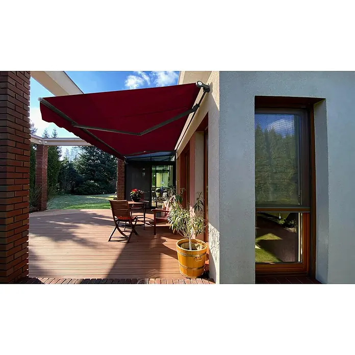 SM Gelenkarmmarkise T-407/11 - Rot, Farbe Gestell: Anthrazitgrau, Breite: 5 m, Ausfall: 3 m - Diese Aufnahme zeigt eine ausfahrbare Markise in einem satten Rotton, die an einer Hauswand montiert ist und Schatten auf eine Terrasse wirft.