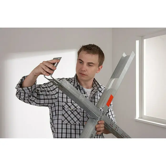 Knauf Türpfostensteckwinkel - 100 x 130 x 135 mm - Mann montiert Trockenbauprofile. Die Profile sind aus Metall und werden für den Innenausbau verwendet.