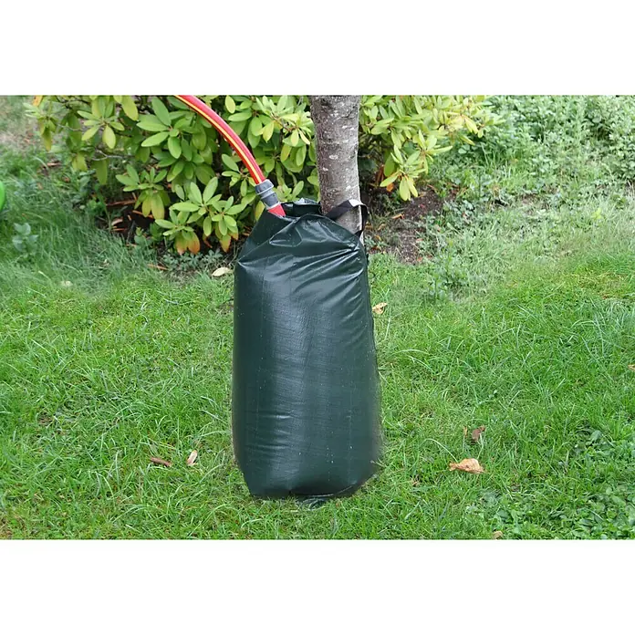 Floraworld Bewässerungssack Classic - Passend für: Bäume bis Ø 18 cm, 190 g/m² - Nahaufnahme eines Baumwassersacks mit rotem Schlauch, der an einem Baum befestigt ist und auf einer grünen Rasenfläche steht.