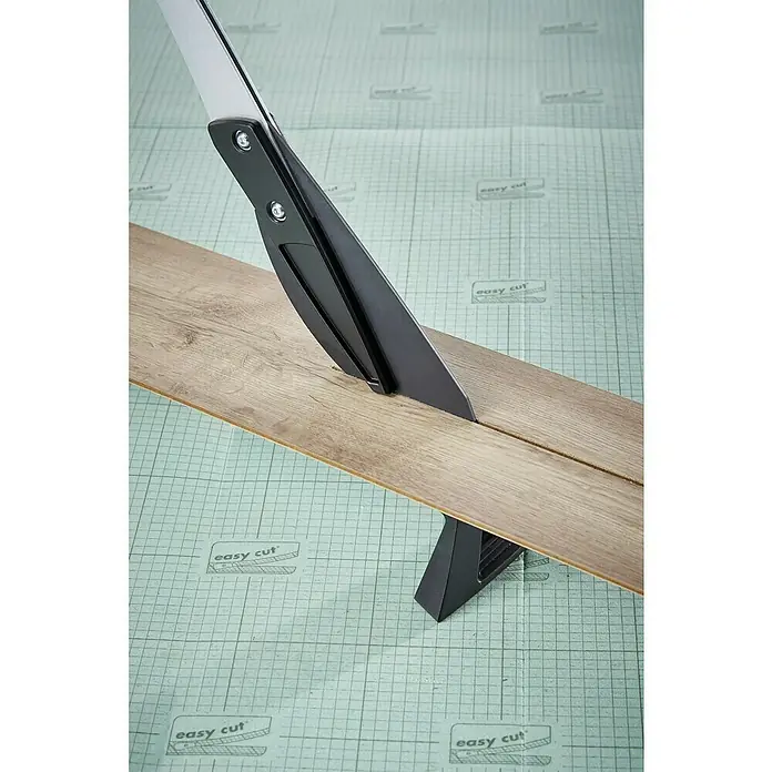 Wolfcraft Laminat- & Vinylschneider VLC 800 - Schnittbreite: 465 mm, Aluminium - Eine Nahaufnahme eines Laminatschneiders, der ein Laminatstück auf einer Arbeitsfläche schneidet. Das Werkzeug ist schwarz mit silbernen Akzenten.