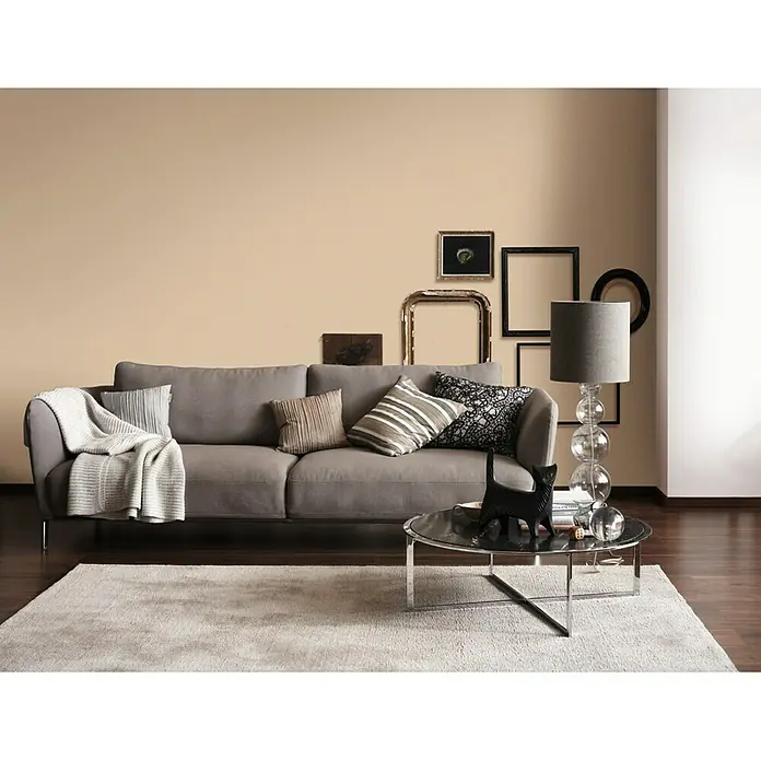 SCHÖNER WOHNEN-Farbe Wandfarbe Trendfarbe - Sand, Matt, 2,5 l, Konservierungsmittelfrei - Gemütliches Wohnzimmer mit grauem Sofa, Zierkissen und einem stilvollen Couchtisch mit Katzenfigur und einer auffälligen Kugel-Lampe.