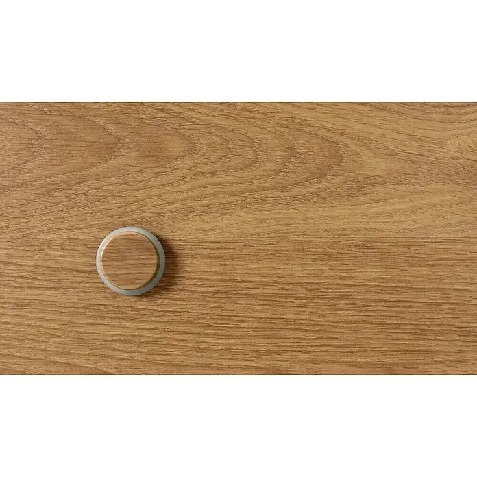 Inofix Tope de puerta 2098 - Ø x Al: 46 x 18 mm, Roble Atlántico - Primer plano de un Apple AirTag sobre una superficie de madera. El AirTag es un pequeño dispositivo redondo con un borde blanco.