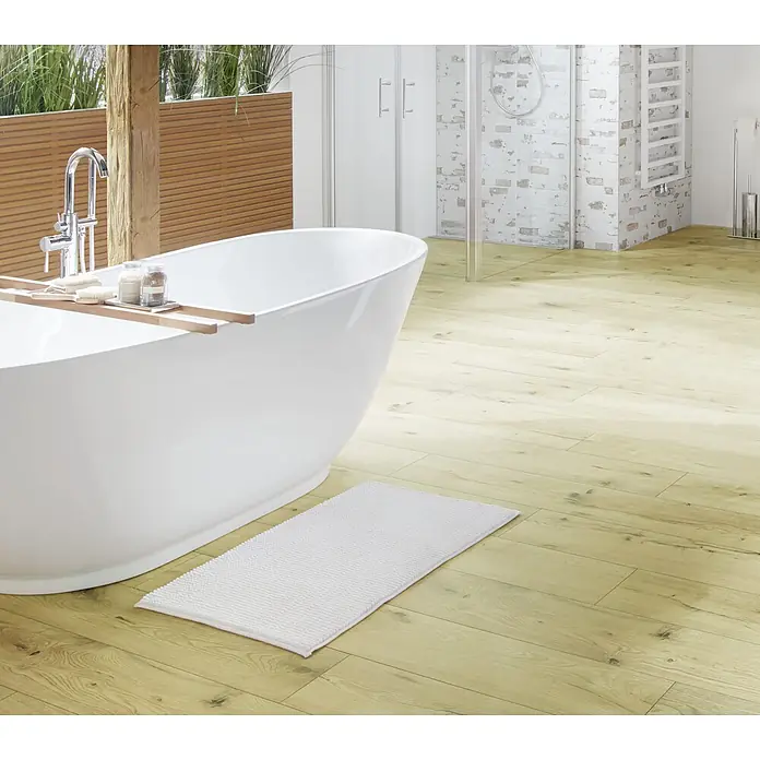 Camargue Badteppich Zottel - 50 x 80 cm, Weiß, 100% Polyester - Ein modernes Badezimmer mit freistehender Badewanne und hellem Holzboden, ergänzt durch eine flauschige, weiße Badematte.
