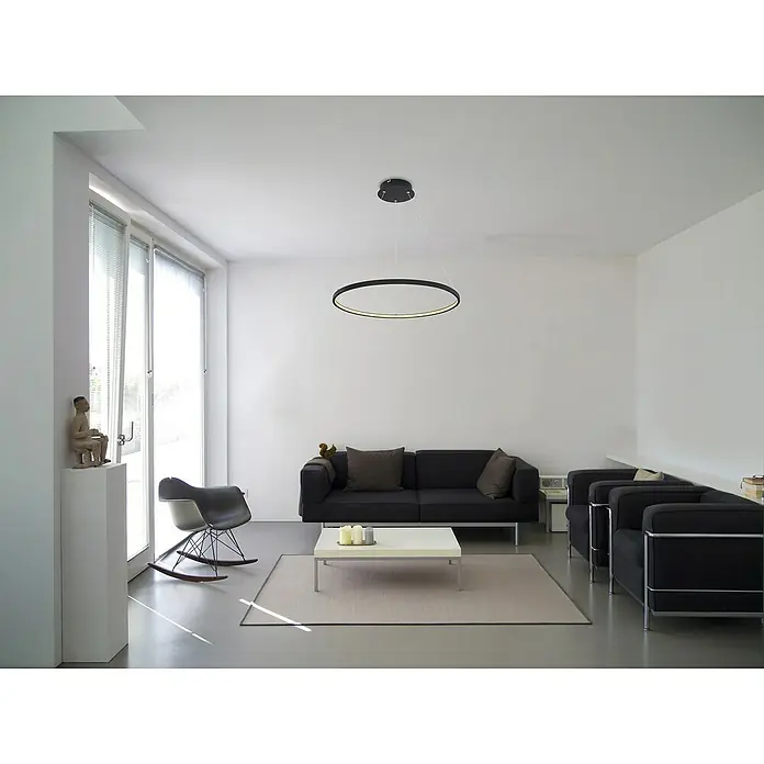 Globo LED-Pendelleuchte Ralph - Ø x H: 60,5 x 120 cm, 29 W, Warmweiß - Minimalistisches Wohnzimmer mit rundem Deckenleuchter, schwarzem Sofa und Sesseln. Die Beleuchtung sorgt für eine moderne Atmosphäre.