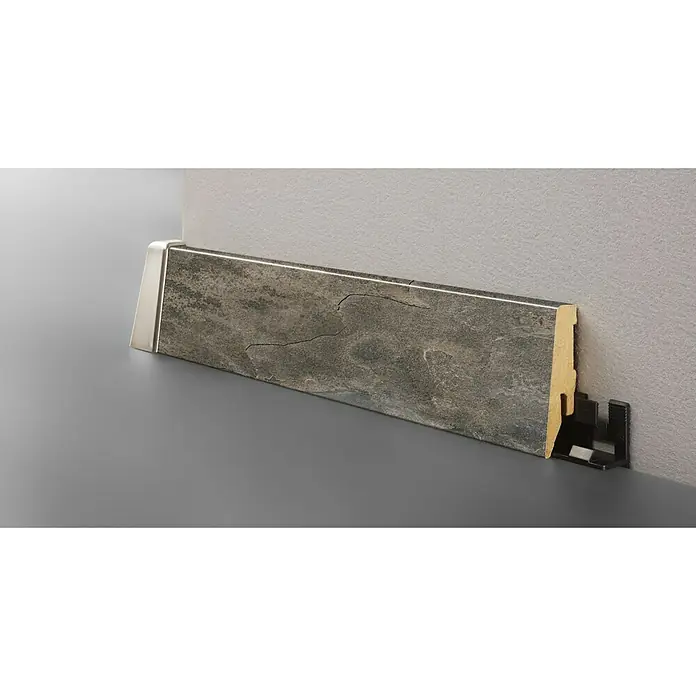 LOGOCLIC Sockelleiste K58 C Silent - 260 cm x 18 mm x 58 mm, MDF - Das Bild zeigt eine moderne Sockelleiste in Steinoptik, die an einer Wand befestigt ist. Die Leiste ist mit einem silbernen Abschluss versehen.