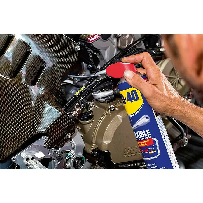 WD-40 Lubricante Multi-Uso Flexible - 400 ml - Primer plano de un producto multiuso flexible WD-40 con boquilla rociadora que se aplica a un motor de motocicleta.