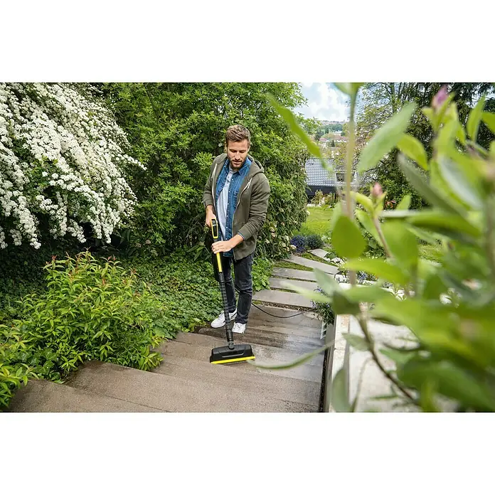 Kärcher Flächenreiniger Powerschrubber PS 30 - Passend für: Kärcher Hochdruckreiniger K2 - K7 - Ein Mann reinigt mit einem Kärcher Flächenreiniger eine Außentreppe. Das Gerät ist gelb und schwarz.