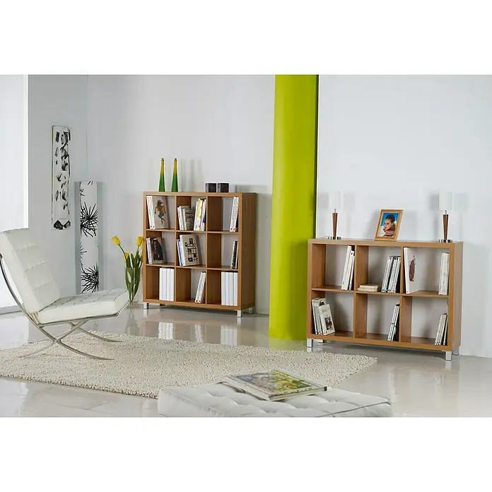 Estantería de madera Kubox - Al x An x Pr: 153 x 76 x 29 cm, Número de baldas: 8 ud., Arce - Salón luminoso con dos estanterías de madera. Las estanterías están llenas de libros y objetos decorativos, junto a un sillón blanco.