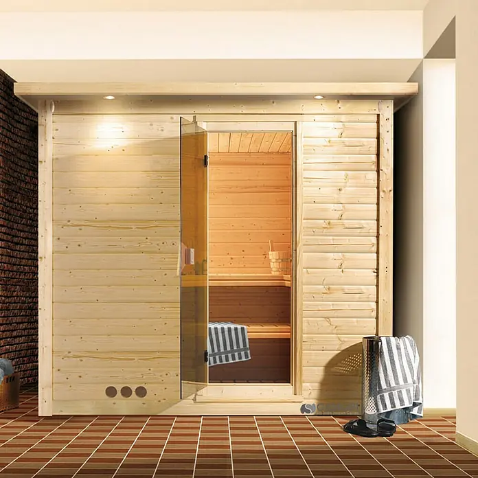 Karibu Elementsauna Mojave - Mit 9 kW Bio-Ofen mit externer Steuerung, Mit Dachkranz und Beleuchtung, Materialspezifizierung Tür: Ganzglas Bronze, L x B x H: 224 x 210 x 192 cm - Eine moderne Holzsauna mit Glastür, die einen Einblick ins Innere mit Holzbänken und Zubehör bietet. Handtücher und Badeschuhe liegen bereit.